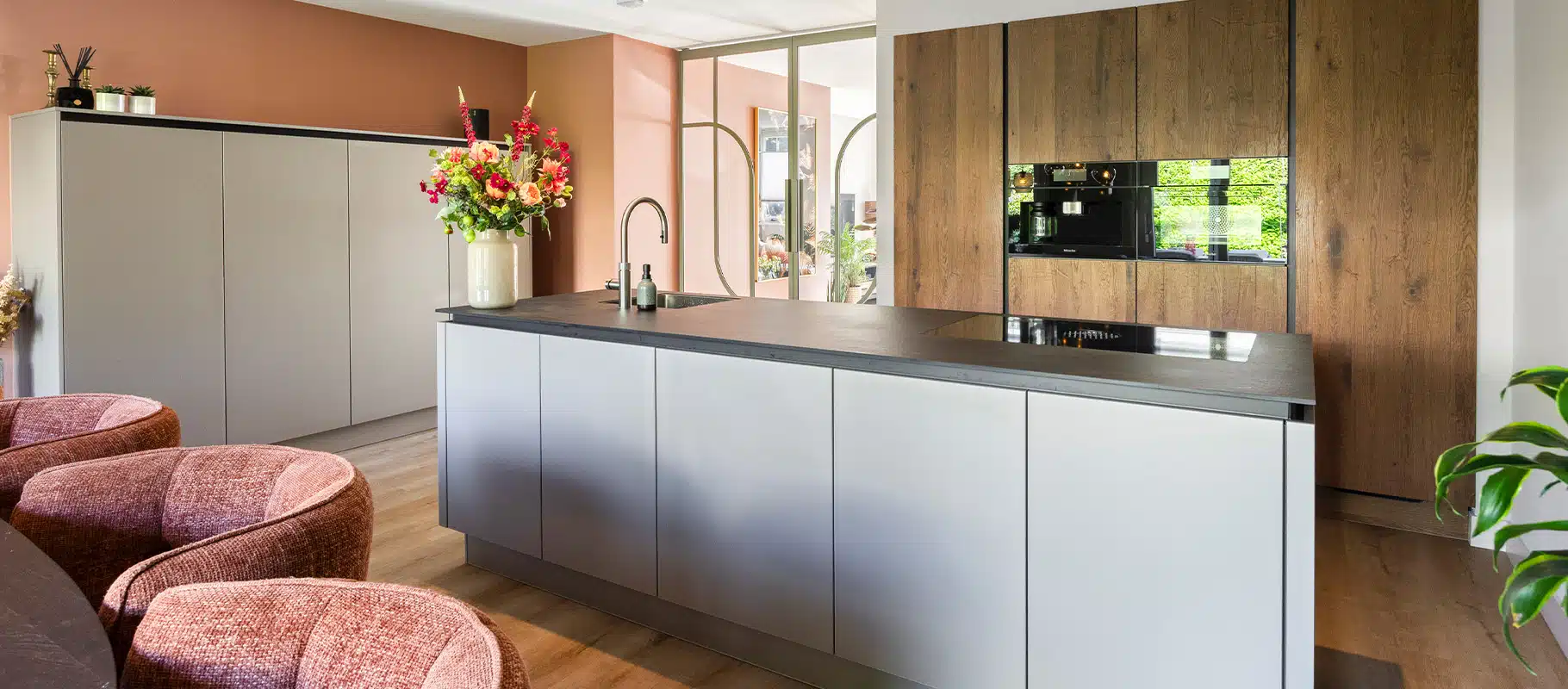 Keuken met licht grijze greeploze fronten, eiken wandkastenwand en zacht perzikkleurige achterwand